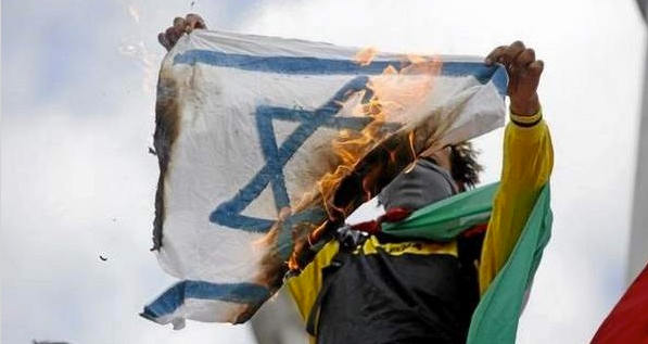 A pro-Palestinian demonstrator holds up a burning Israeli flag on the Republique square in Paris, during a banned demonstration against Israel’s military operation in Gaza and in support of the Palestinian people, on July 26, 2014. (KENZO TRIBOUILLARD/AFP/Getty Images)