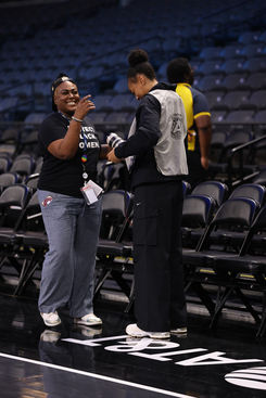 Allisha Gray in a photo vest stands on the court and takes pre-game photos