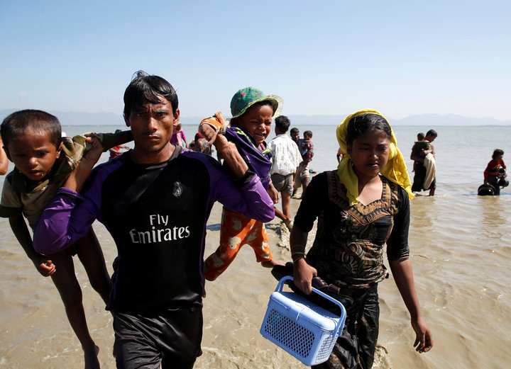 NAVESH CHITRAKAR / REUTERS A Rohingya refugee man holding children walks towards the shore as they arrive on a makeshift boat after crossing the Bangladesh-Myanmar border, at Shah Porir Dwip near Cox’s Bazar, Bangladesh, Nov. 9, 2017.