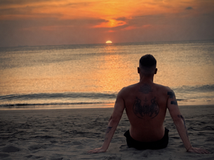 Benni blickt am Strand von Koh Lanta auf den Sonnenuntergang über dem Meer