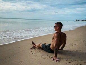 Benni sitzt am Strand von Khao Lak und blickt auf das Meer