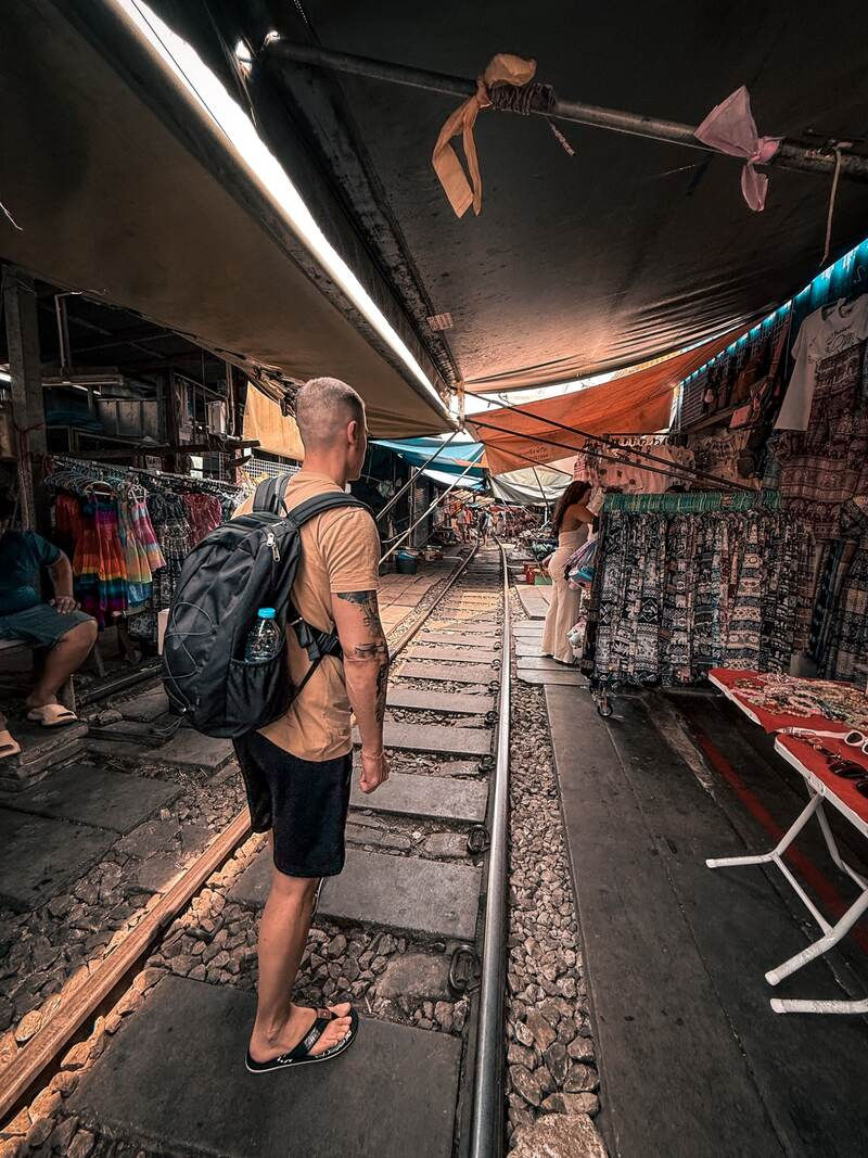 Benni mit schwarzem Tagesrucksack auf dem Maeklong Railway Market in Thailand