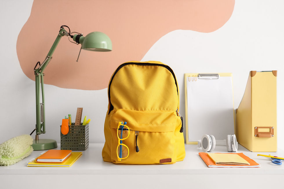 Workspace with school supplies and backpack near color wall.jpg