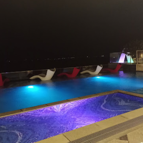 Night pool with blue and purple lights and lounge chairs