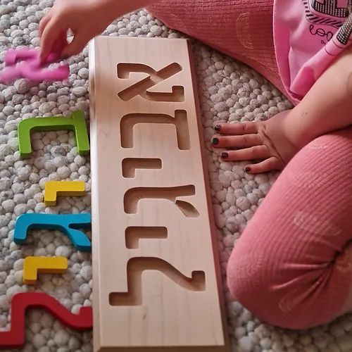 ילדה משחקת עם פאזל שם מעץ