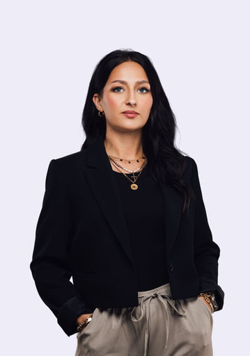 Businessportrait einer Frau in schwarzem Blazer mit beiger Hose.