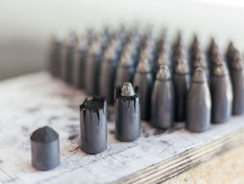 Reihen identischer zylindrischer Metallteile mit abgerundeten Köpfen.