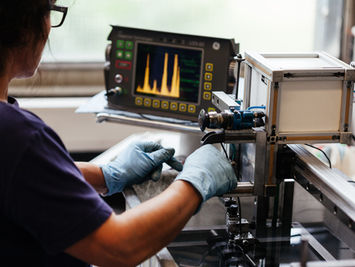 Person arbeitet zur Qualitätskontrolle an einer industriellen Maschine .