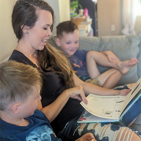 A mother reading the MarlaGran book to her two young sons, sharing a playful moment of connection and storytelling.