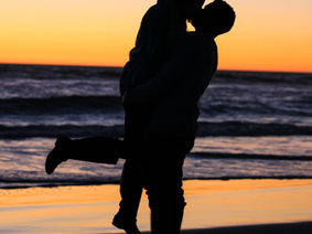 Silhouetted couple kissing at sunset by the ocean, symbolizing deep, flowing love, trust, and connection beyond fleeting passion.