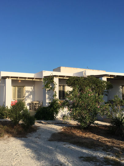Traditional island architecture showcasing the exterior of retreat rooms surrounded by lush green bushes at the Feminine Wholeness Retreat location.