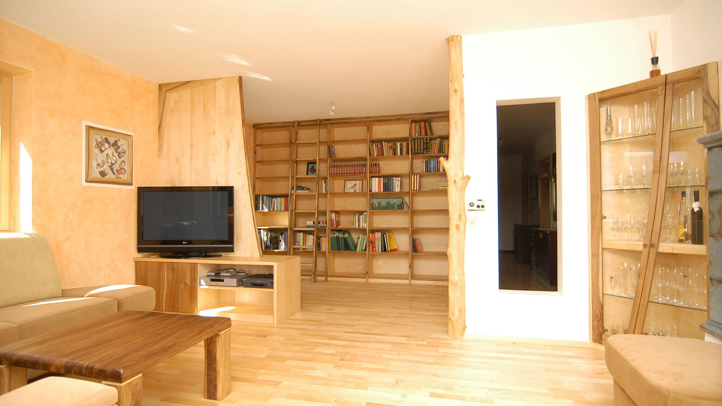 Wohnzimmer aus Birke und Nussbaum mit Bücherwand, Glasvitrine, TV Möbel und Baumstamm als Raumelement