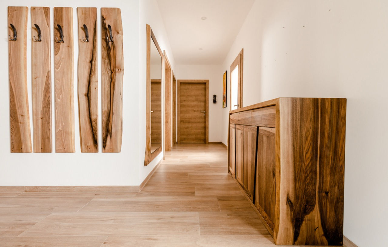 Garderobe aus massivem Nussbaum nach Maß mit Naturkante, Kommode, Wandpaneelen und flächenbündigem Spiegel in einem modernen Eingangsbereich