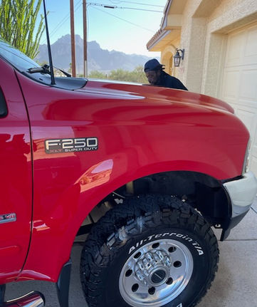 Red F250 truck parked near a house with mountains in the background.