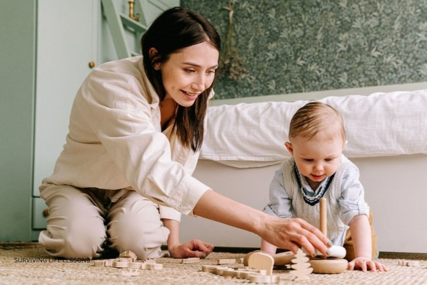 A mother joyfully plays on the floor with her toddler, guiding them through wooden toys.