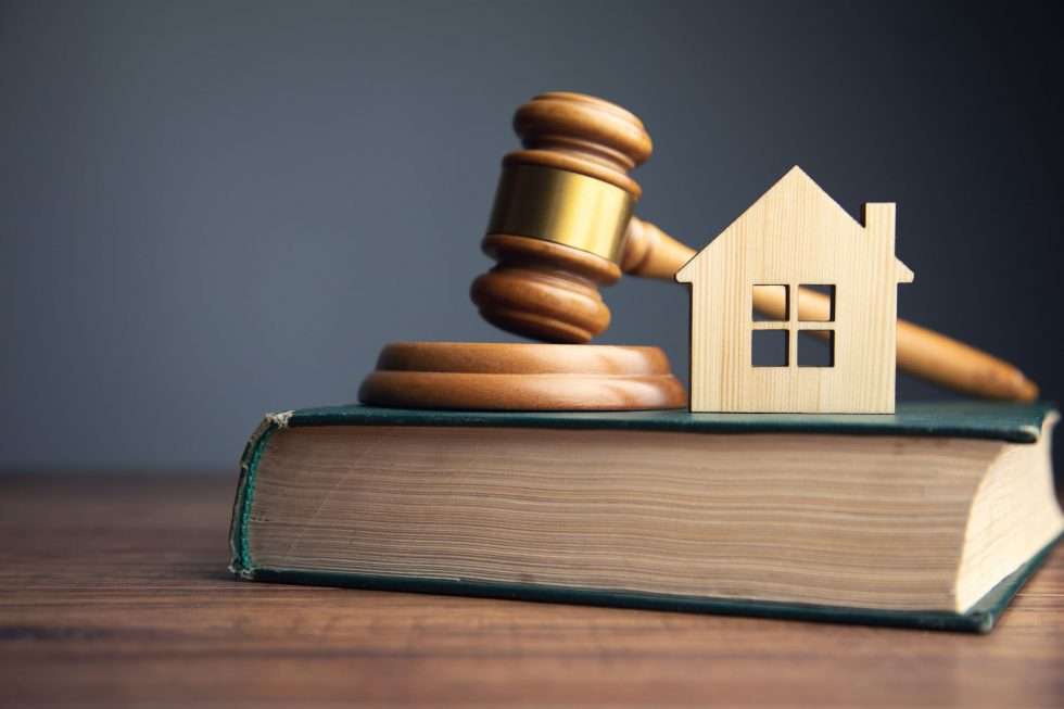 A property and a gavel on top of a book, signifying that the book is about property law. 