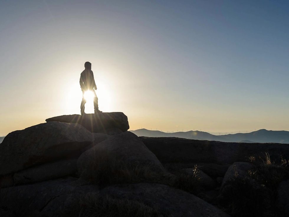 Leader standing on a rocky overlook at sunrise, symbolizing reflection, purpose, and personal growth