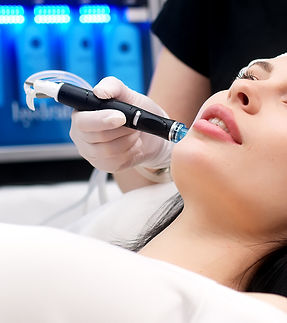 Cosmetology clinic. Professional female cosmetologist doing hydrafacial procedure while be