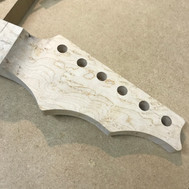 Tuner holes in a heavily figured bords eye maple guitar headstock