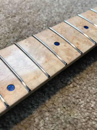 Final polish to follow - the image the 12th to 7th frets on an attractive birds eye maple guitar neck. The fingerboard has transparent blue acrylic position markers which show silver beneath