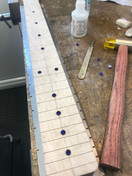 Fret markers Inserting fret markersLocating the fret markers -  the image shows a partially completed Malone Guitars electric guitar neck. The neck is made from birds eye maple. Pencil marks show the centres of the fret dots. The fret markers are made from transparent blue acrylic