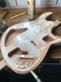 Glue up - the mahogany back of an electric guitar lays on a workbench. The wood is in the process of being covered with glue