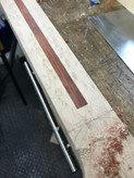 Skunk stripe installation - -  the image shows a partially completed Malone Guitars electric guitar neck. The neck is made from birds eye maple and the stripe is made from bubinga