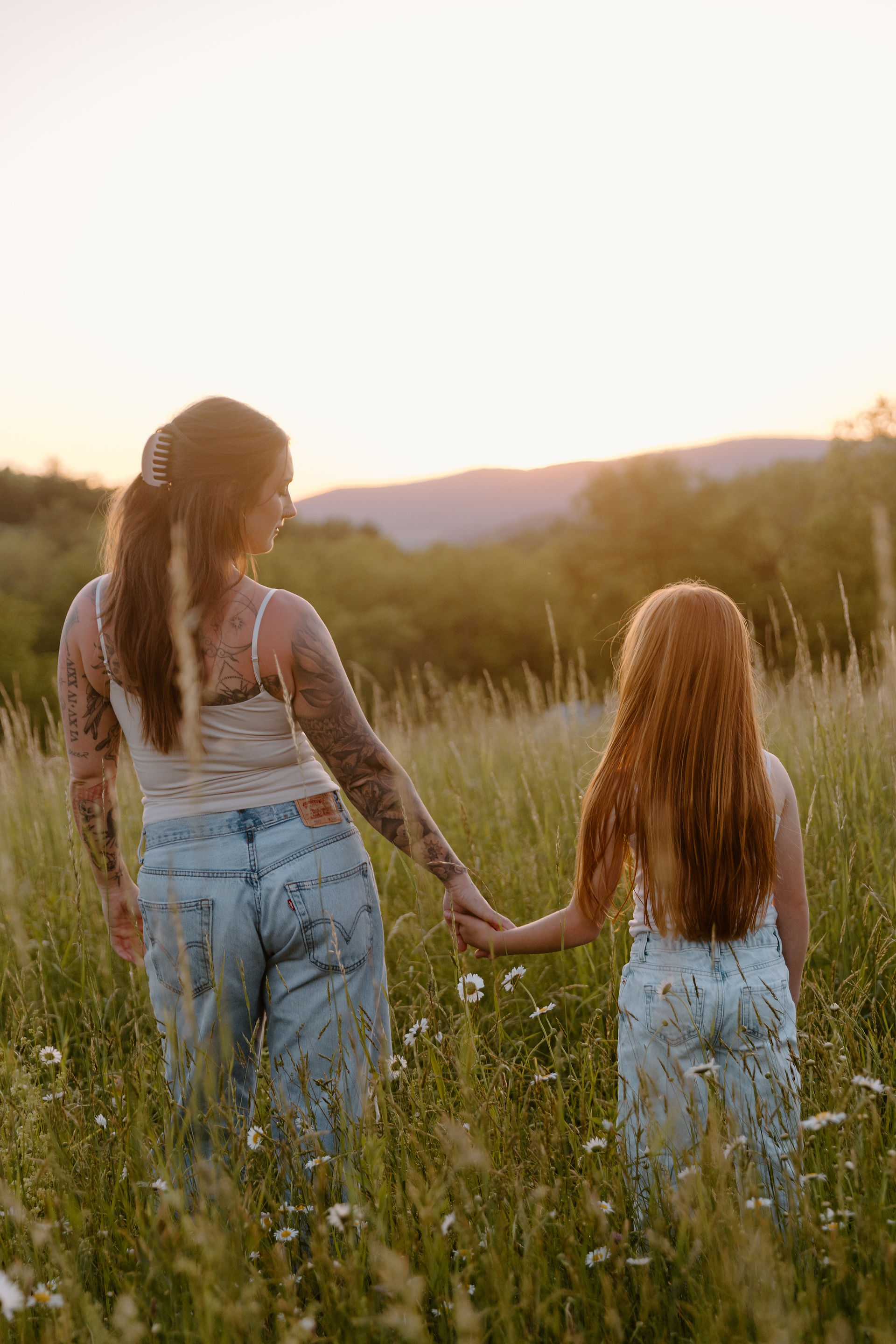 Mom and daughter holding hands in Williamsport Pennsylvania wildflower field during family session