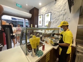 Customer place order at the kiosk while staff focus on preparing their order in Shawarma Shack outlet