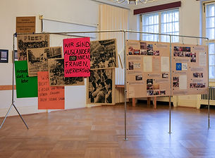 A number of posters hanged on a metal-structure in a space that looks like a gallery.