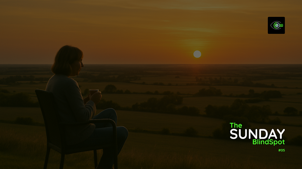 A woman sits cross-legged in an outdoor chair, holding a cup of tea with both hands, gazing toward a vivid sunset over a vast countryside landscape. The scene is calm and reflective. In the bottom right corner, white and green text reads “The Sunday BlindSpot #05,” with a green and black eye logo in the top right. (Love you Nic - 1974-2025)