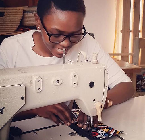 Close-up view of Conchetta, a Tanzanian artisan sewing a colorful fabric pouch