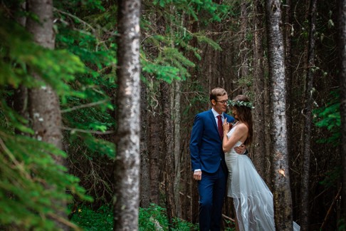 Bride and groom embracing in the trees in Kananaskis.