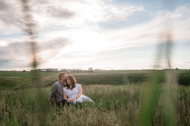 Couple sitting in grass, groom kissing bride on head, sitting together, summer engagement photos, country photos, meadow