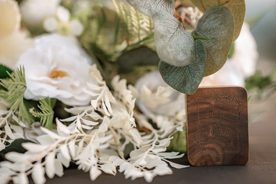 Close-up of a personalized wooden wedding ring box surrounded by white flowers styled as part of an intimate Kananaskis elopement
