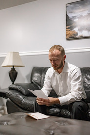 A close-up of the groom beginning to read a handwritten card, getting a bit emotional.