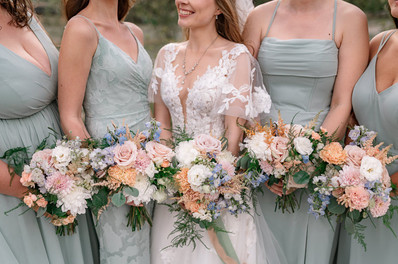 Bride standing with her bridesmaids holding pastel bouquets during portraits at one of the most scenic Canmore wedding venues, with the Canadian Rockies creating a stunning mountain backdrop.