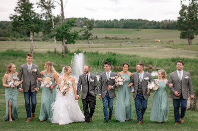The bridal party walks together across the lawn at Daimond in the Rough, smiling and laughing alongside the newlyweds