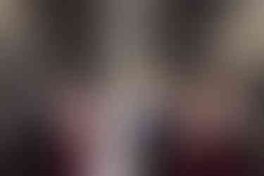 Bride and groom looking at eachother with bridal party behind them