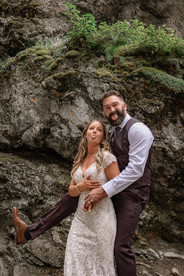 Bride and groom embracing together against a rocky backdrop on their Crowsnest Pass wedding day