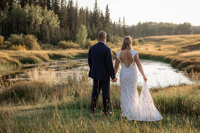 Bride and groom looking away at a pond