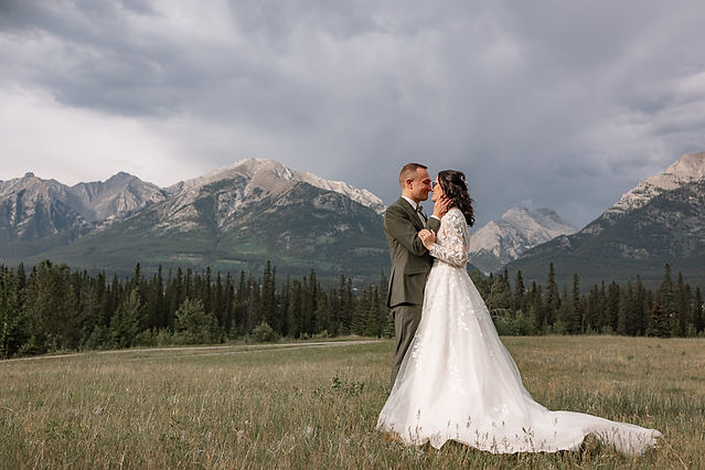 couple kissing in a field with the mountains behind