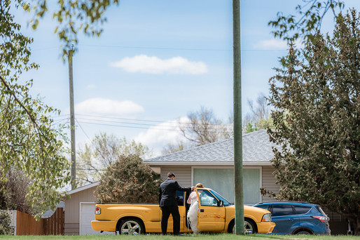 Bride and groom leaving ceremony in yellow truck 