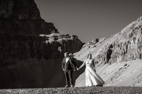 bride and groom hold hands with mountains in the back black and white photo