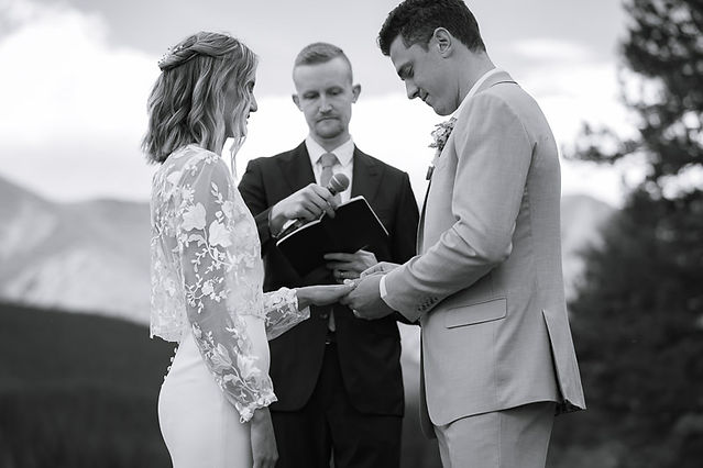 Bride and groom exchanging rings as the officiant watches during an intimate outdoor ceremony at a Kananaskis wedding