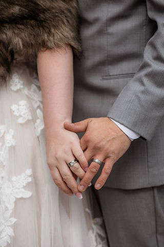 Detail shot of bride and grooms hands with rings visible
