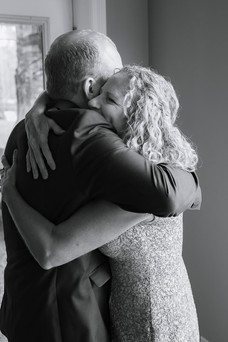 Heartfelt getting ready moments as the groom shares hugs, laughter, and boutonniere details with loved ones before a romantic farm wedding.