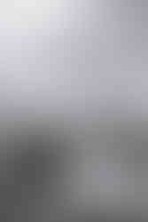 Black and white candid of the bride and groom twirling on the dance floor under chandelier inside a rustic barn during their first dance