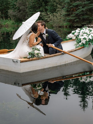 Bride and groom kissing in a boat with reflection