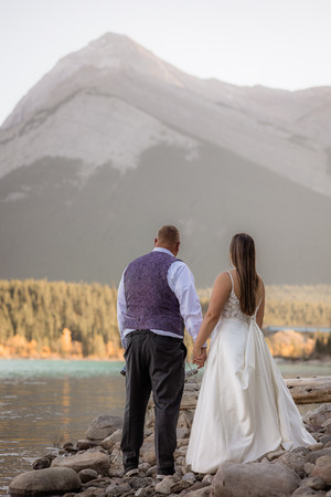 bride and groom hold hands and look out over lake